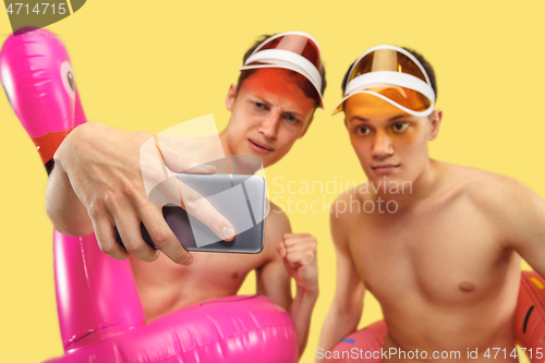 Image of Two young men isolated on yellow studio background