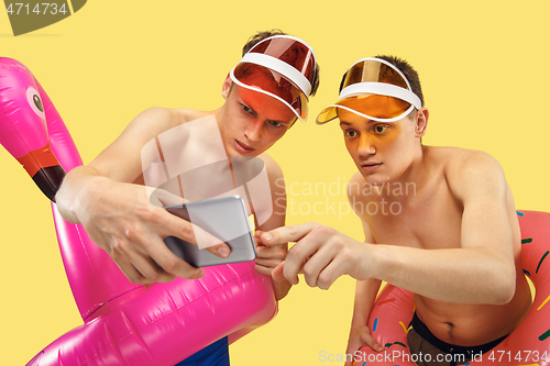 Image of Two young men isolated on yellow studio background