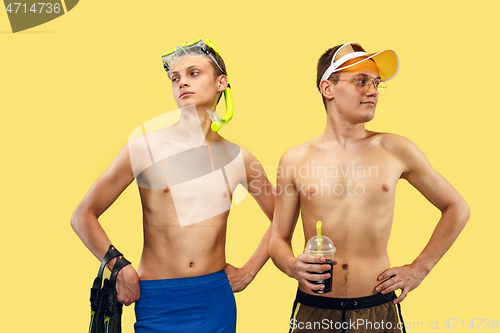 Image of Two young men isolated on yellow studio background