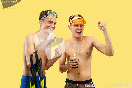 Image of Two young men isolated on yellow studio background