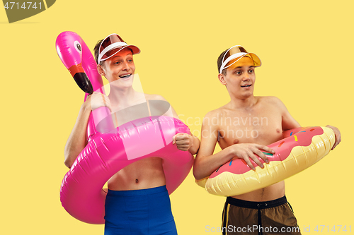 Image of Two young men isolated on yellow studio background