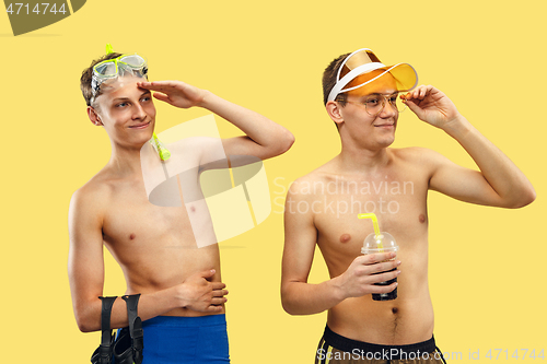 Image of Two young men isolated on yellow studio background