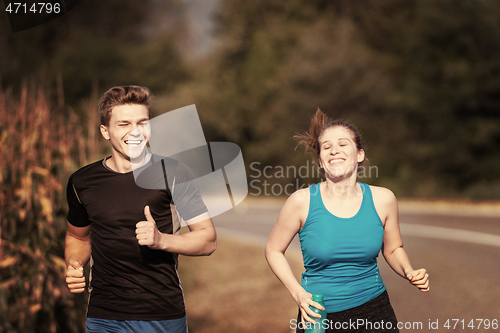Image of young couple jogging along a country road