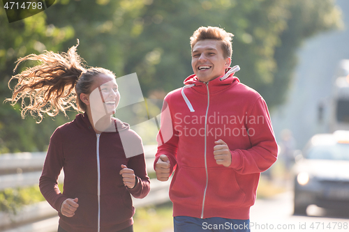 Image of young couple jogging along a country road
