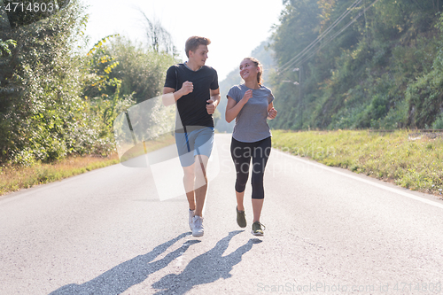 Image of young couple jogging along a country road