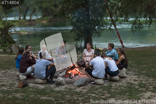 Image of young friends relaxing around campfire