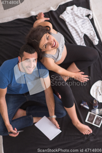 Image of top view of couple checking a list of things for their unborn ba