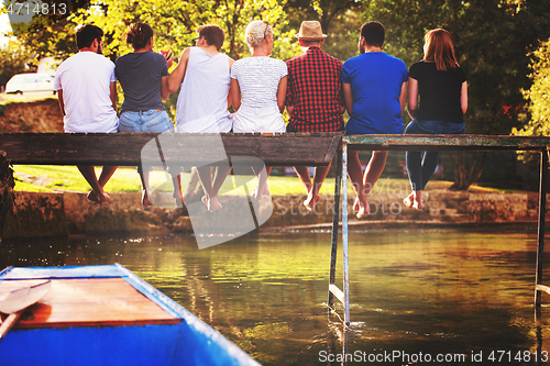 Image of rear view of friends enjoying watermelon while sitting on the wo