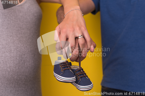 Image of couple holding newborn baby shoes