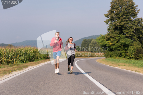 Image of young couple jogging along a country road