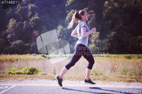 Image of woman jogging along a country road