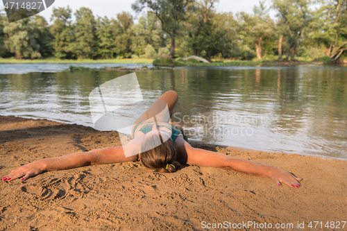 Image of girl in a green bikini relaxing on the riverbank