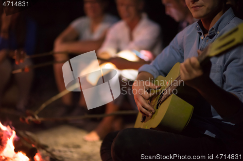 Image of young friends relaxing around campfire