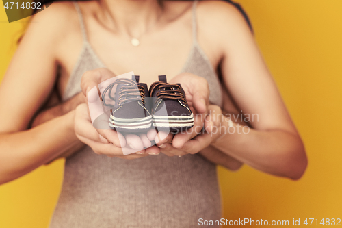 Image of couple holding newborn baby shoes