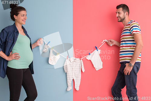 Image of young couple holding baby bodysuits