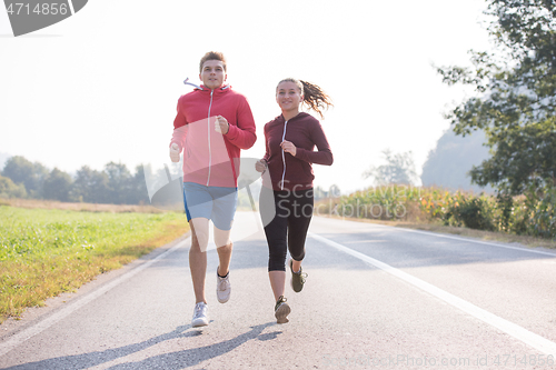 Image of young couple jogging along a country road