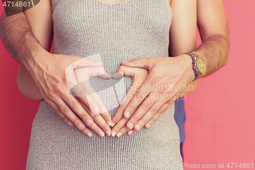 Image of pregnant  couple showing heart with their hands