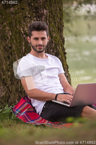 Image of man using a laptop computer on the bank of the river