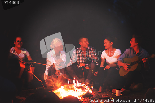 Image of young friends relaxing around campfire