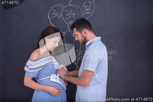 Image of pregnant couple drawing their imaginations on chalk board