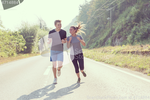 Image of young couple jogging along a country road