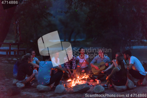 Image of young friends relaxing around campfire