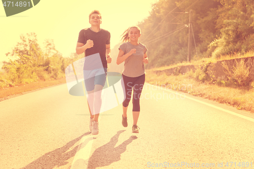 Image of young couple jogging along a country road