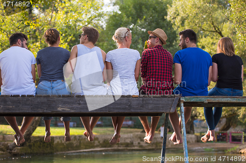 Image of rear view of friends enjoying watermelon while sitting on the wo