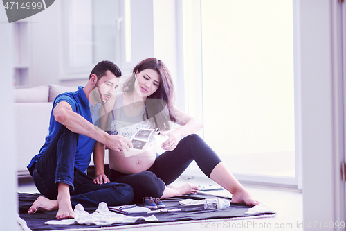 Image of pregnant couple checking a list of things for their unborn baby