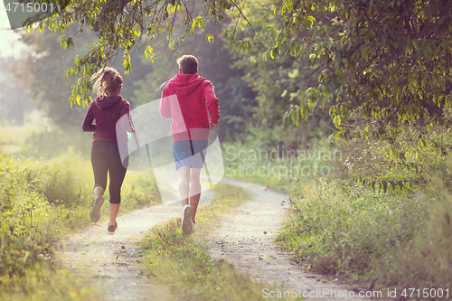 Image of young couple jogging along a country road