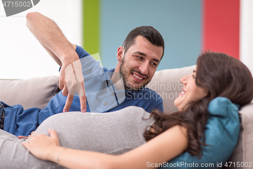 Image of young pregnant couple relaxing on sofa