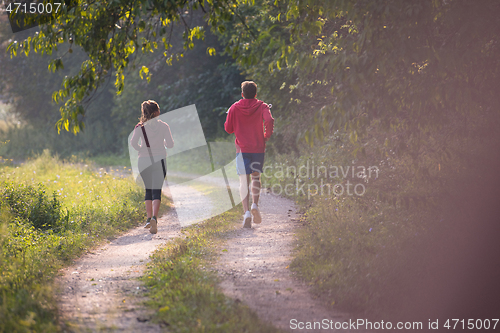 Image of young couple jogging along a country road