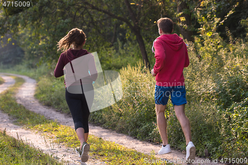 Image of young couple jogging along a country road