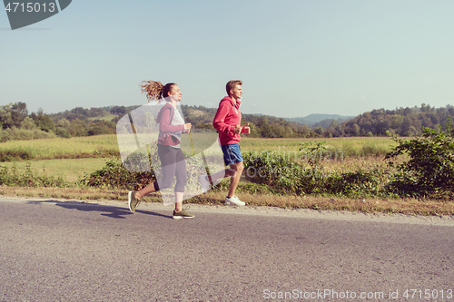 Image of young couple jogging along a country road