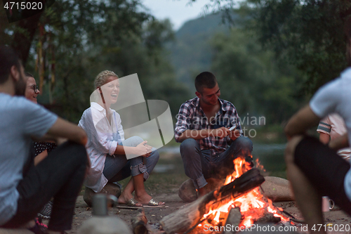 Image of young friends relaxing around campfire