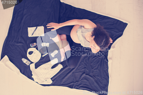 Image of top view of pregnant woman checking list of baby clothes