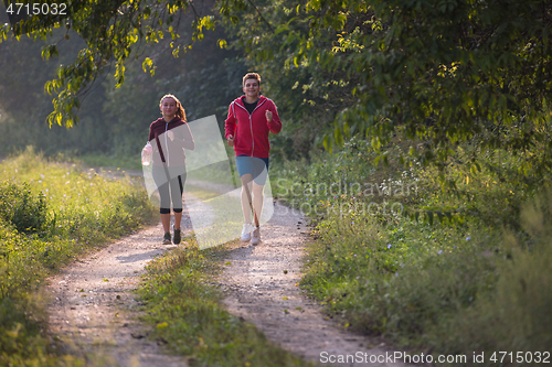 Image of young couple jogging along a country road