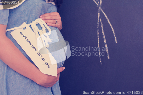 Image of Portrait of pregnant woman in front of black chalkboard