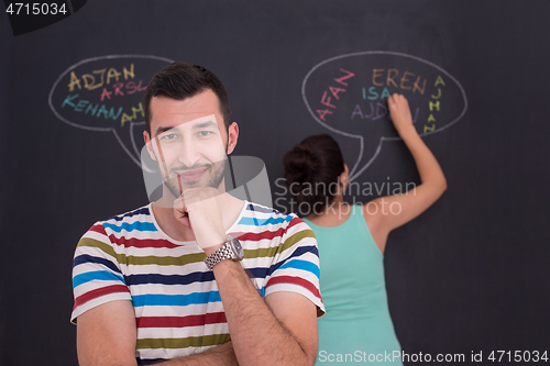 Image of pregnant couple writing on a black chalkboard