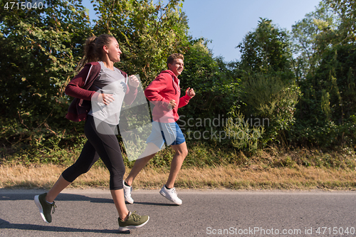 Image of young couple jogging along a country road