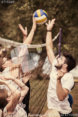 Image of group of young friends playing Beach volleyball