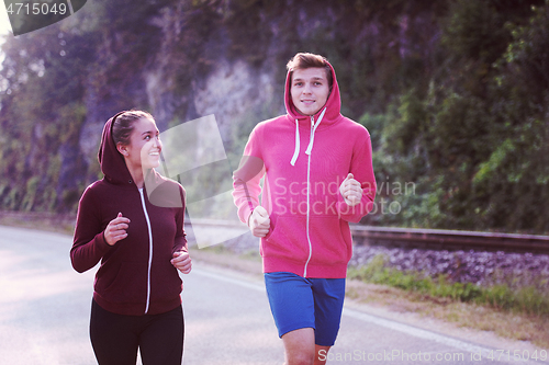 Image of young couple jogging along a country road