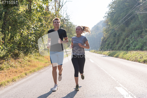 Image of young couple jogging along a country road