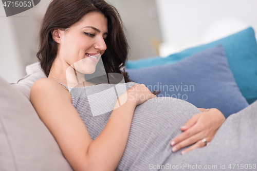 Image of pregnant woman sitting on sofa at home