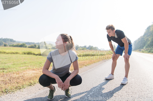 Image of young couple warming up and stretching on a country road