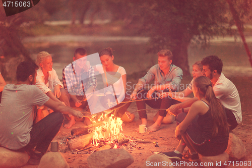 Image of young friends relaxing around campfire