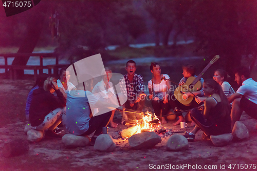 Image of young friends relaxing around campfire