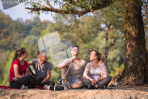 Image of friends smoking hookah on the river bank