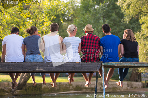 Image of rear view of friends enjoying watermelon while sitting on the wo