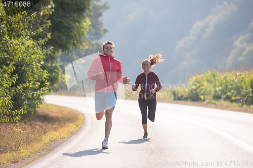 Image of young couple jogging along a country road